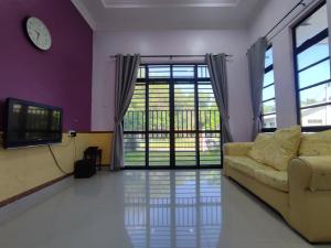 a living room with a couch and a tv at NikNa Homestay Batu Rakit - WIFI in Kampong Ru Tujoh