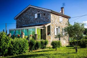una vieja casa de piedra con cortinas verdes. en L'Armourier, en Largentière