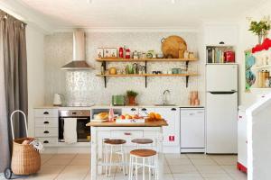 a kitchen with white appliances and a counter with stools at Fuller Holidays - Get Sandy - Beachside Byron in Byron Bay