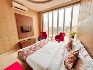 een slaapkamer met een groot bed en 2 rode stoelen bij The Peral Lodge - A beautiful lavish & luxuries Family Hotel in Zirakpur