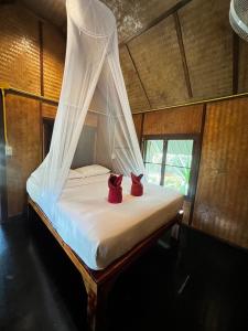 two red shoes sitting on a bed in a room at Khaosok Bamboo Huts Resort in Khao Sok National Park