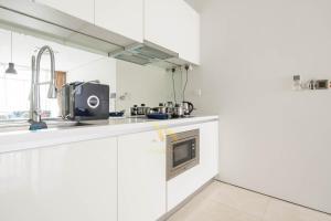 a white kitchen with a sink and a microwave at Soho Suites KLCC by Minsha in Kuala Lumpur