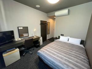 Habitación de hotel con cama y escritorio con ordenador en Route Inn Grantia Naha, en Naha