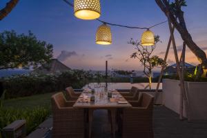 una mesa de comedor con sillas y luces en un patio en Samabe Bali Villas, en Nusa Dua