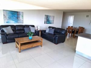 ein Wohnzimmer mit schwarzen Ledersofas und einem Tisch in der Unterkunft Supa Sized 3 bedroom 2 bath in Gold Coast