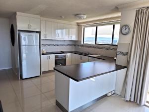 eine Küche mit weißen Schränken und einem weißen Kühlschrank in der Unterkunft Supa Sized 3 bedroom 2 bath in Gold Coast