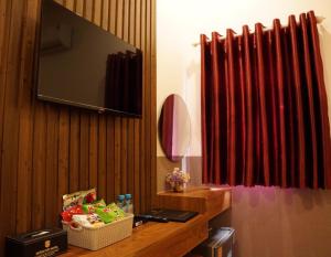 a room with a television on a wooden wall with a table at Hoàng Tây Hotel - Đồng Tháp in Ấp Hòa Lạc