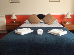 2 toallas en una cama azul con 2 lámparas en Welbeck Hotel - Close to Beach, Train Station & Southend Airport, en Southend-on-Sea