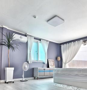 a bedroom with blue walls and a bed and a window at Aewol Torini in Jeju