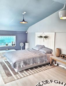 a bedroom with a large bed and a blue wall at Aewol Torini in Jeju