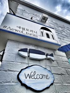 a welcome sign on a building with a boat on it at Aewol Torini in Jeju