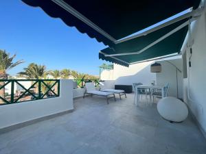 a patio with a table and chairs and a balcony at Barbican in Playa Honda