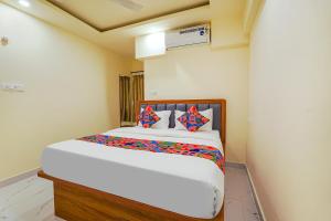 FabHotel Happy Home Stays في بانغالور: غرفة نوم مع سرير أبيض كبير مع وسائد ملونة