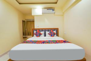 1 dormitorio con 1 cama blanca grande con almohadas coloridas en FabHotel Happy Home Stays, en Bangalore