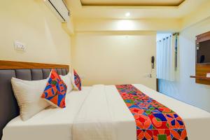 FabHotel Happy Home Stays في بانغالور: غرفة نوم مع سرير أبيض مع وسائد ملونة