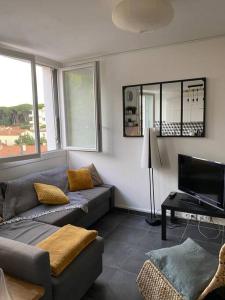 ein Wohnzimmer mit einem Sofa und einem TV in der Unterkunft Charmant appartement quartier école d’agronomie in Montpellier