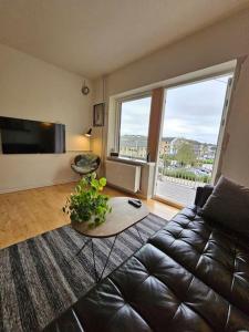 uma sala de estar com um sofá de couro e uma mesa em Lejlighed med altan og gratis parkering em Aalborg