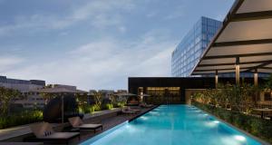 a swimming pool with lounge chairs and a building at Hilton Garden Inn Bengaluru Embassy Manyata Business Park in Bangalore