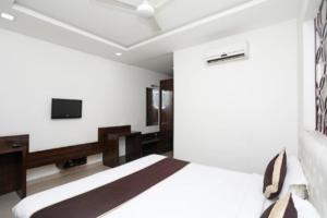 Hotel Areeba by The Golden Taj Group & Hotels في آغْرا: غرفة نوم بسرير وتلفزيون بشاشة مسطحة