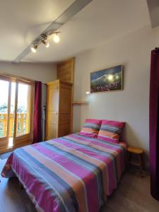 1 dormitorio con 1 cama con una manta a rayas de colores en Le Gypaète en Morillon