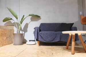 a living room with a blue couch and a plant at Walk Home Hostel in Chiayi City