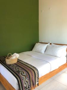a bedroom with a white bed with a green wall at Escape Bajo in Labuan Bajo