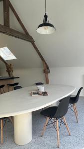 una gran mesa blanca con sillas y una lámpara en Gezellige loft met twee slaapkamers en Ypres