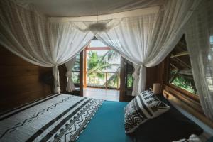 a bedroom with a bed with curtains and a window at Favela Mentawai in Tua Pejat