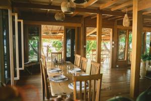 a dining room with a wooden table and chairs at Favela Mentawai in Tuapejat
