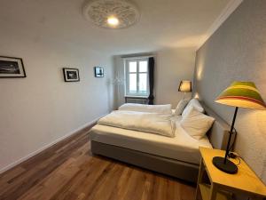een slaapkamer met een bed met een lamp en een tafel bij Lakeside Apartments Rorschach - easy self check-in in Rorschach