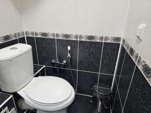 a bathroom with a white toilet and black tiles at Новая 3-х комнатная квартира Мечта in Bukhara