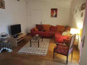 sala de estar con sofá rojo y TV en Le ptit Venton maison écologique pour particulier ou professionnel, en La Jaille-Yvon