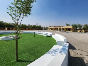 a park with white benches and a small tree at استراحه الليوان ALliwan Rak 1 in Ras al Khaimah