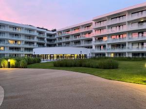 a large apartment building with a lawn in front of it at Blue Dunes Apartament Polanki Aqua in Kołobrzeg