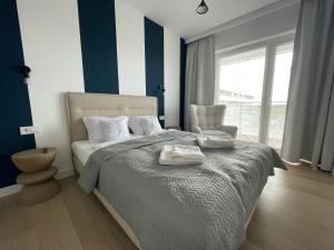 a bedroom with a bed and a chair and a window at Blue Dunes Apartament Polanki Aqua in Kołobrzeg +22 photos