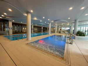 a large swimming pool in a building with a large swimming pool at Blue Dunes Apartament Polanki Aqua in Kołobrzeg