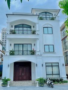 una casa blanca con una motocicleta estacionada frente a ella en Nice Villa Venuestay, en Ha Long