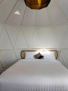 - une chambre avec un grand lit blanc dans une tente dans l'établissement ภูเพียงพอ ณ เชียงราย, à Chiang Rai