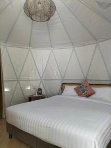 1 dormitorio con 1 cama blanca en una tienda de campaña en ภูเพียงพอ ณ เชียงราย en Chiang Rai