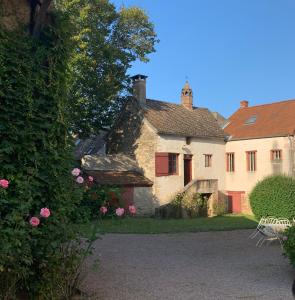 una vieja casa de piedra con rosas rosas en el patio en LES CHARMES en Jugy