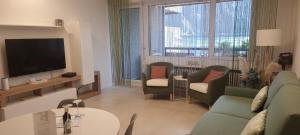 uma sala de estar com um sofá e cadeiras e uma televisão em Relax-Lugano Lake em Bissone