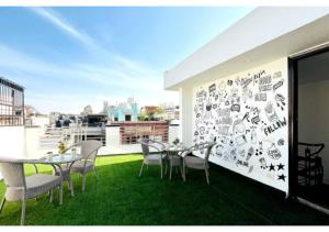 a balcony with tables and chairs and a wall covered in stickers at Olive Service Apartments - Greater Kailash in New Delhi