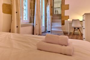 Una cama blanca con una toalla blanca encima. en "La Revenderie", appartement calme sur cour privative, hyper centre de Nevers by PRMO C0NCIERGERIE, en Nevers