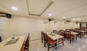 una sala da pranzo con tavoli e sedie in legno di Treebo Trend Sam Residency a Coimbatore