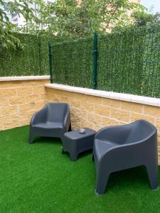 two benches sitting on the grass next to a wall at Apartamentos La Ruta in Calpe