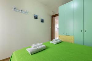 a bedroom with a green bed with two towels on it at Appartamento Al porticciolo in Grado