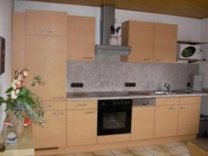 a kitchen with wooden cabinets and a stove top oven at Eifelferienhaus Thome - a34701 in Lissendorf
