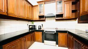 a kitchen with wooden cabinets and a stove top oven at Olive Serviced Apartments - Defence Colony in New Delhi