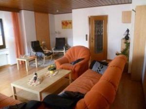 a living room with an orange couch and a table at Eifelferienhaus Thome - a34701 in Lissendorf