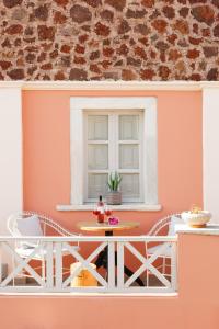a balcony with a table and chairs and a window at The Museum Project Oia in Oia